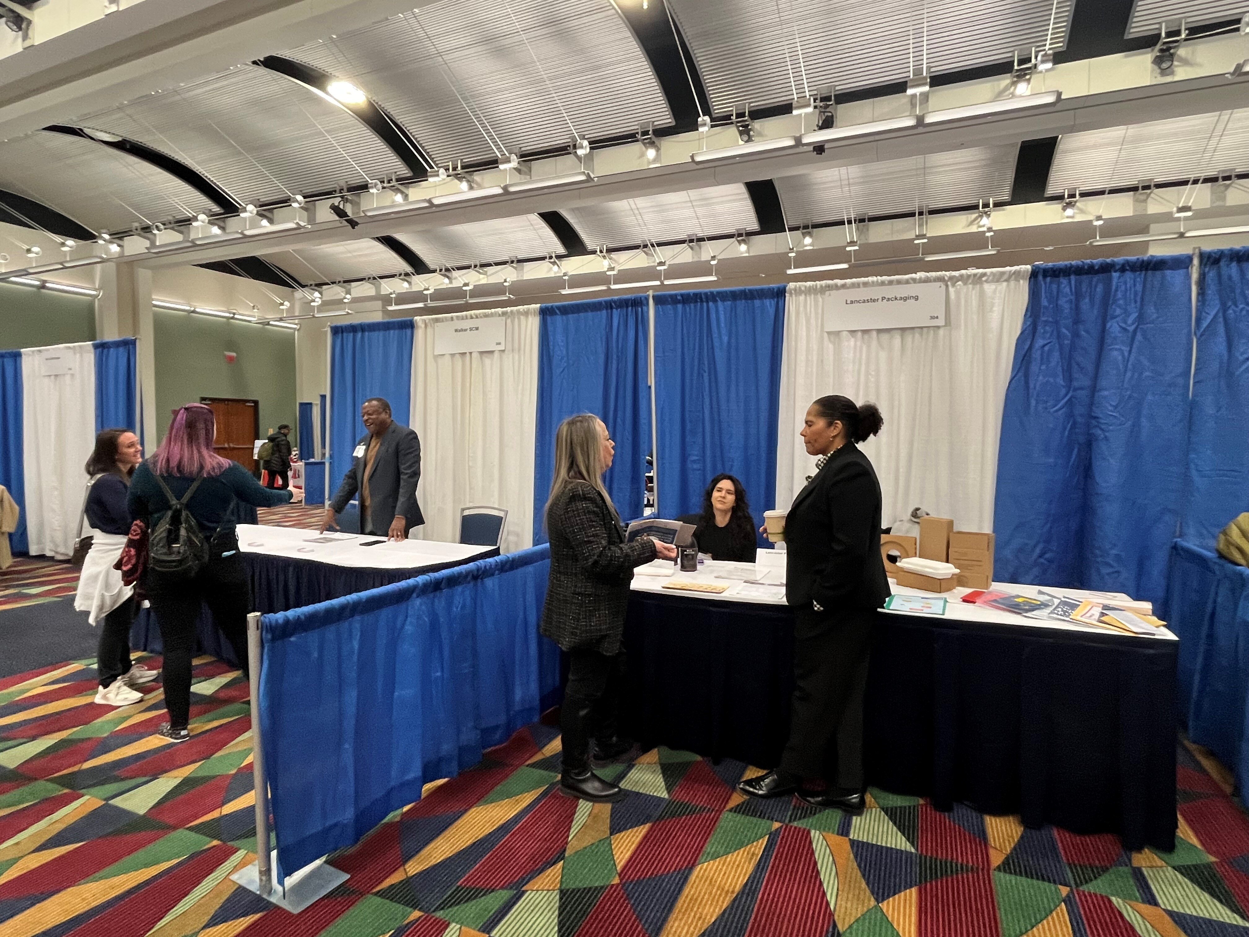 Two booths with business representatives are shown at the Keolis DBE fair in Worcester