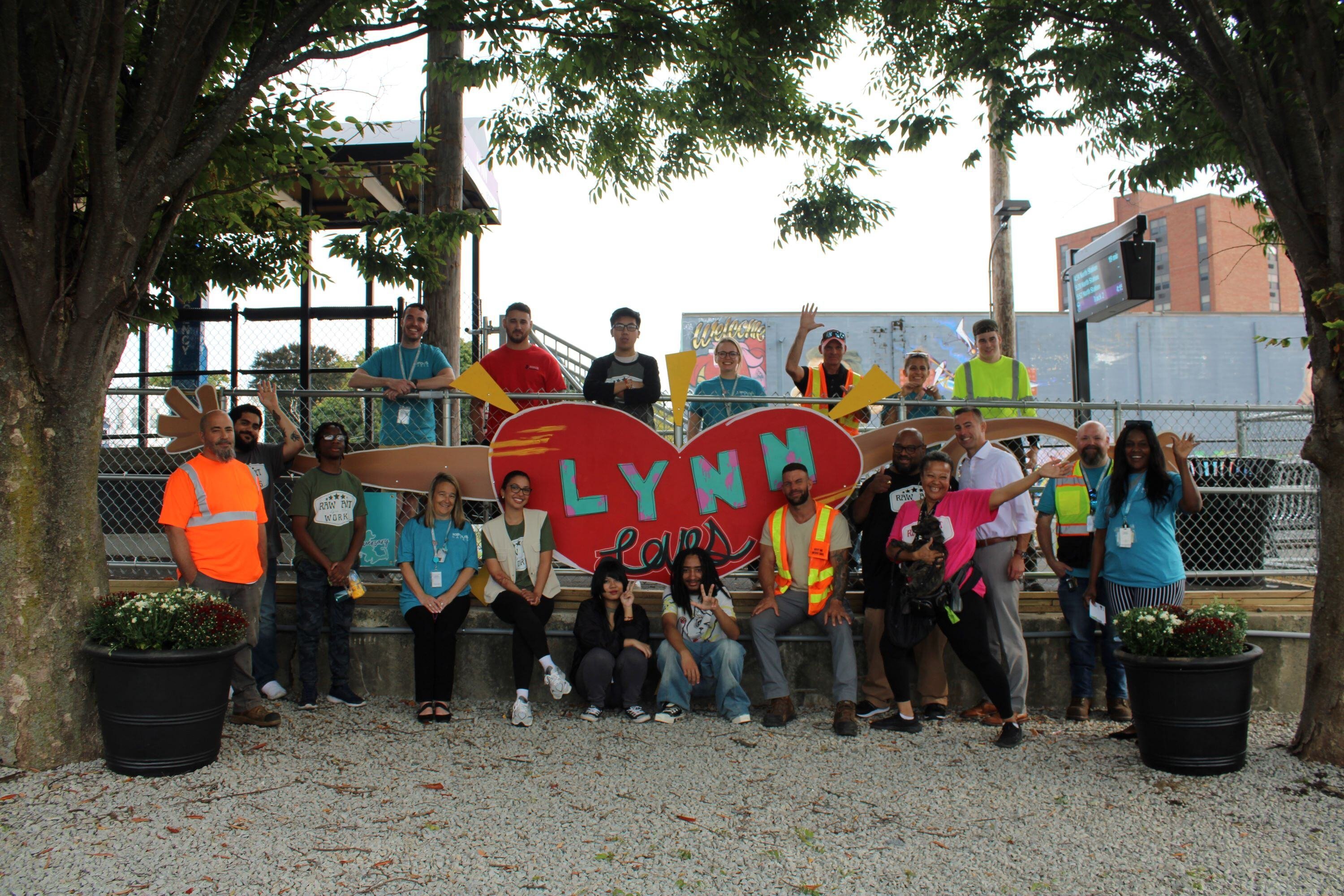 A group of local artists and Keolis volunteers pose with a new art installation at Lynn Station