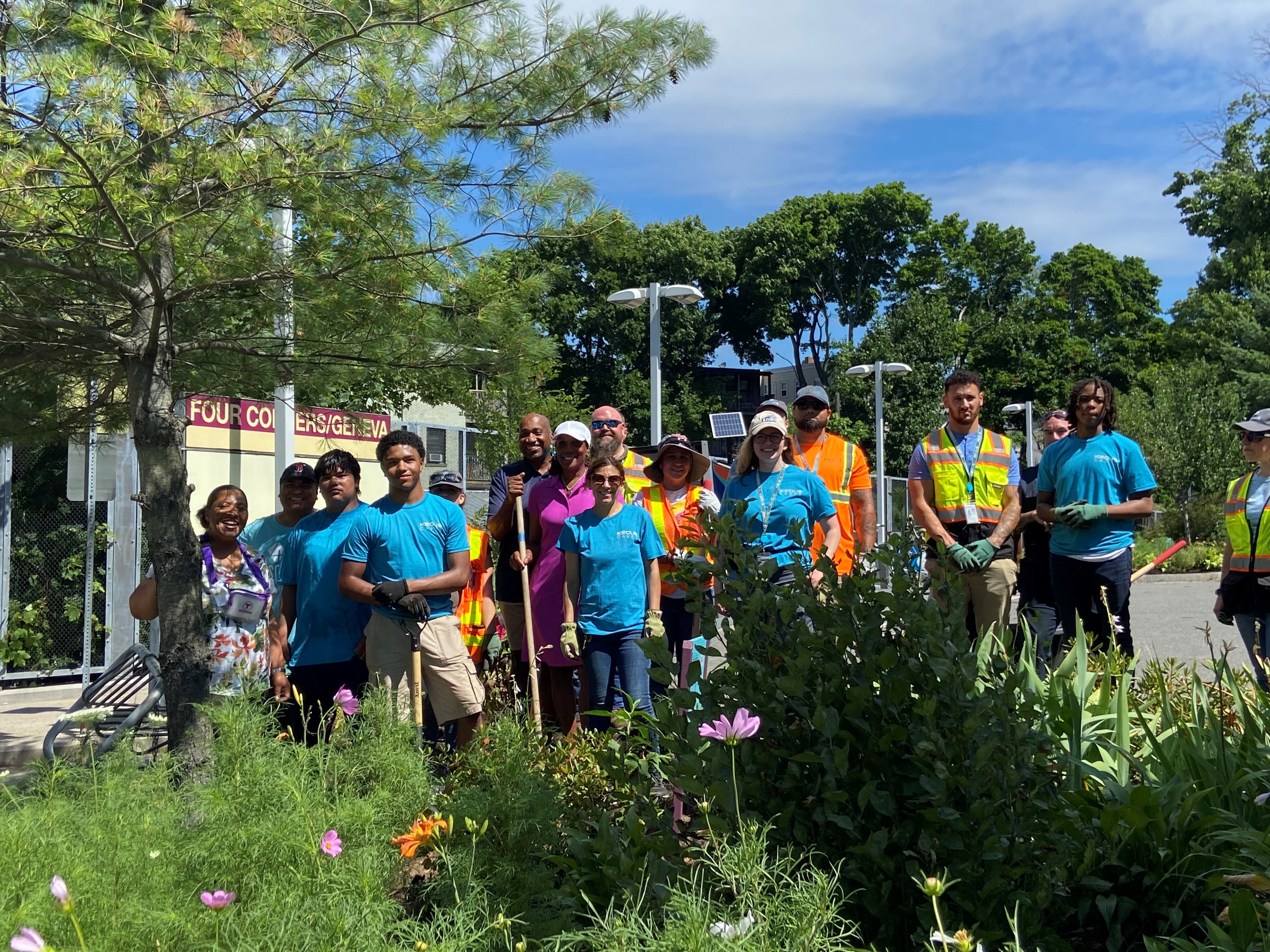 A group of Keolis employees and volunteers plant flowers at Four Corners Station
