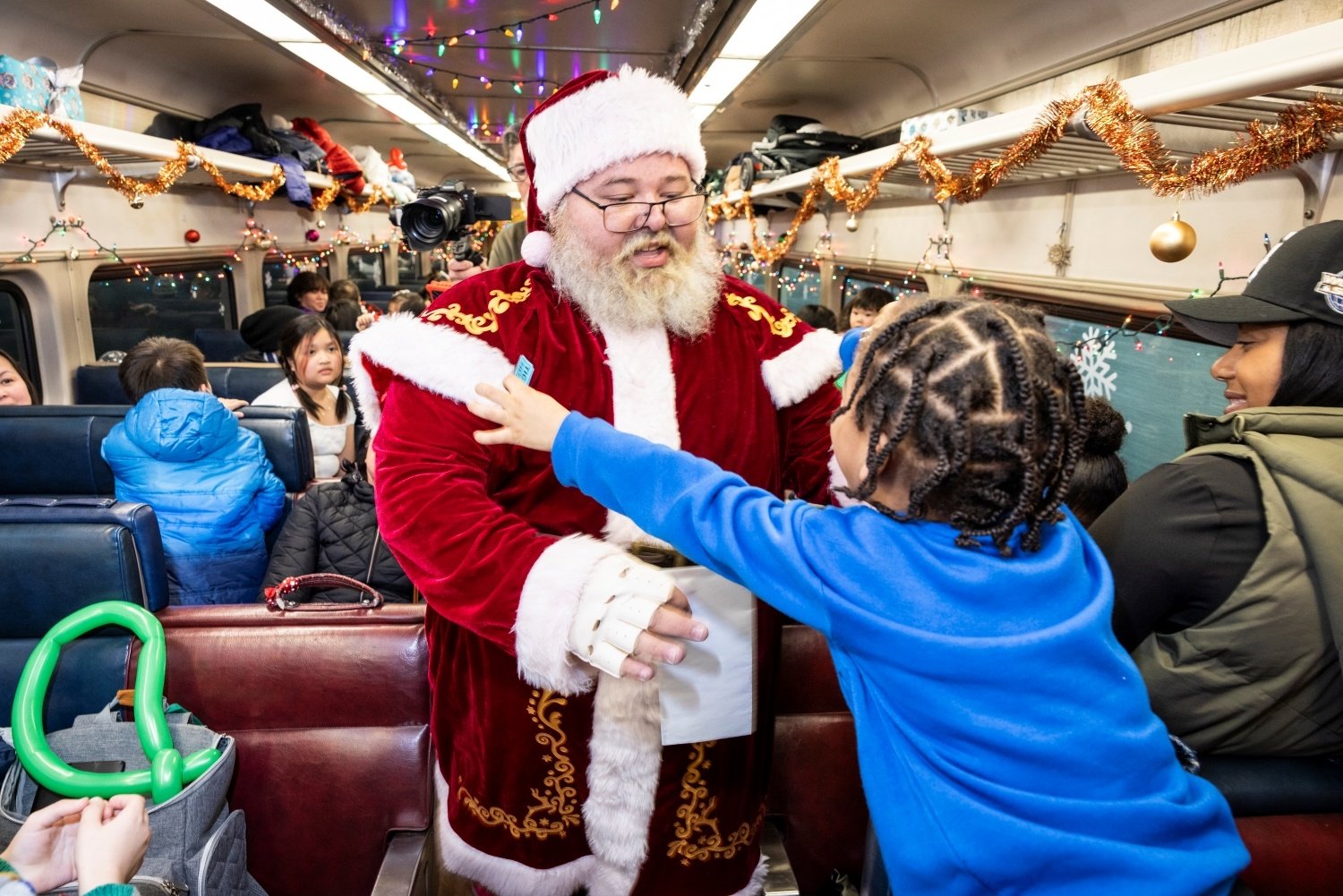 Santa Claus greets a child on board the North Pole Express Commuter Rail train